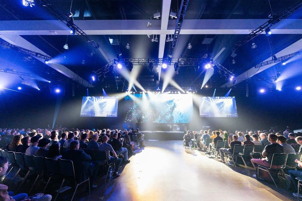 Corporate event stage with lights, screens and a seated audience